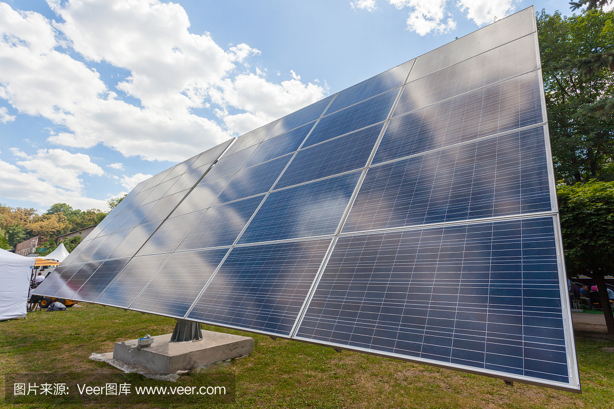 替代太阳能概念。低角度顶侧视图照片的太阳能电池板元素反对绿色的自然和清澈的蓝天